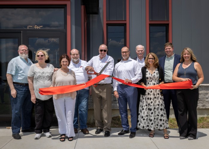 Group cutting red ribbon at grand opening