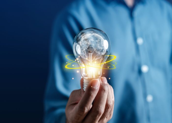 Hand holding glowing digital globe lightbulb