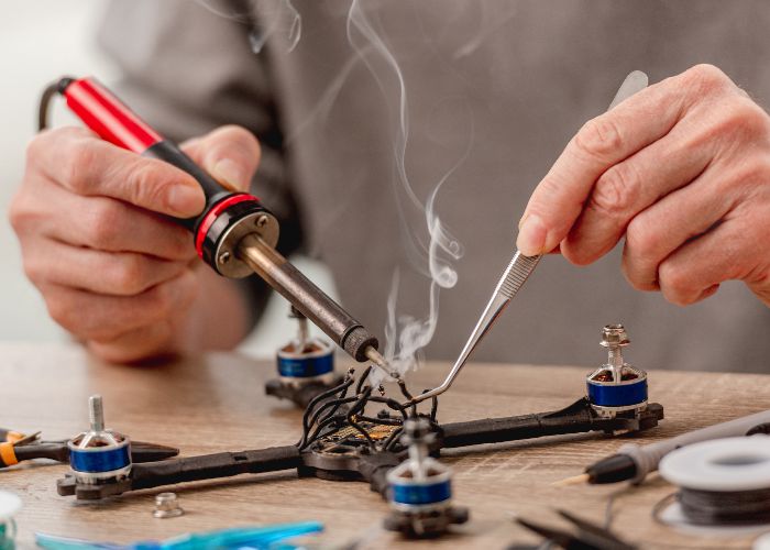 Hands soldering quadcopter drone wiring