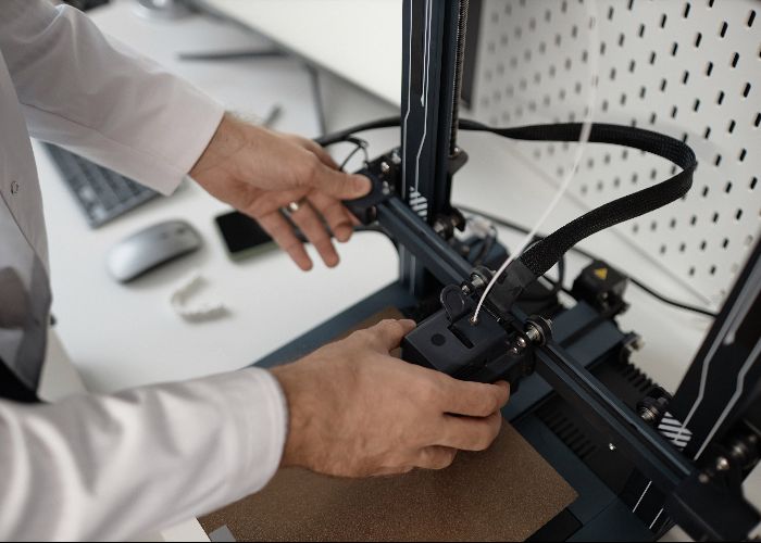 Hands adjusting desktop 3D printer extruder